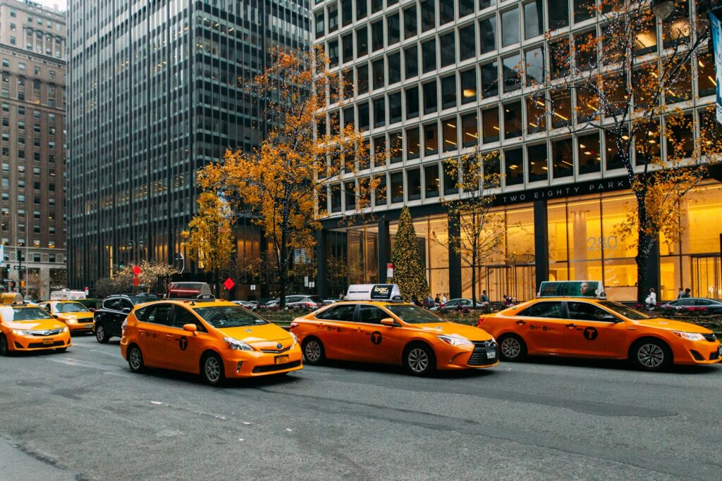 yellow taxi cab on road near high rise buildings during daytime